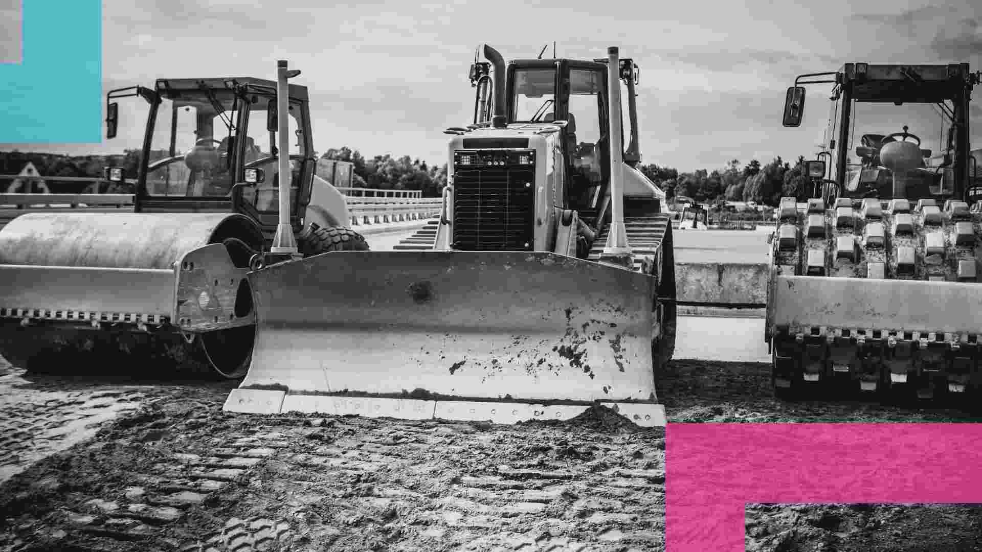 Three pieces of heavy machinery parked side by side in a muddy worksite