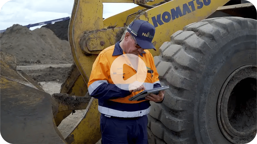 Man in hi vis doing a risk assessment on a heavy machine in the background