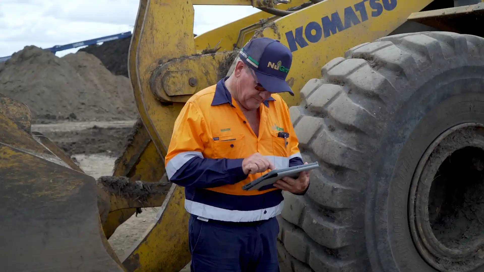 Man in hi vis doing a risk assessment on a heavy machine in the background