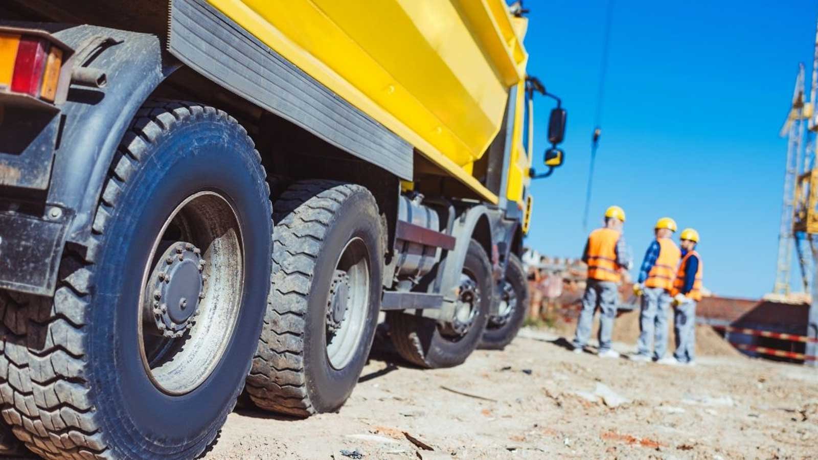 Men standing next to a big dump truck on a worksite