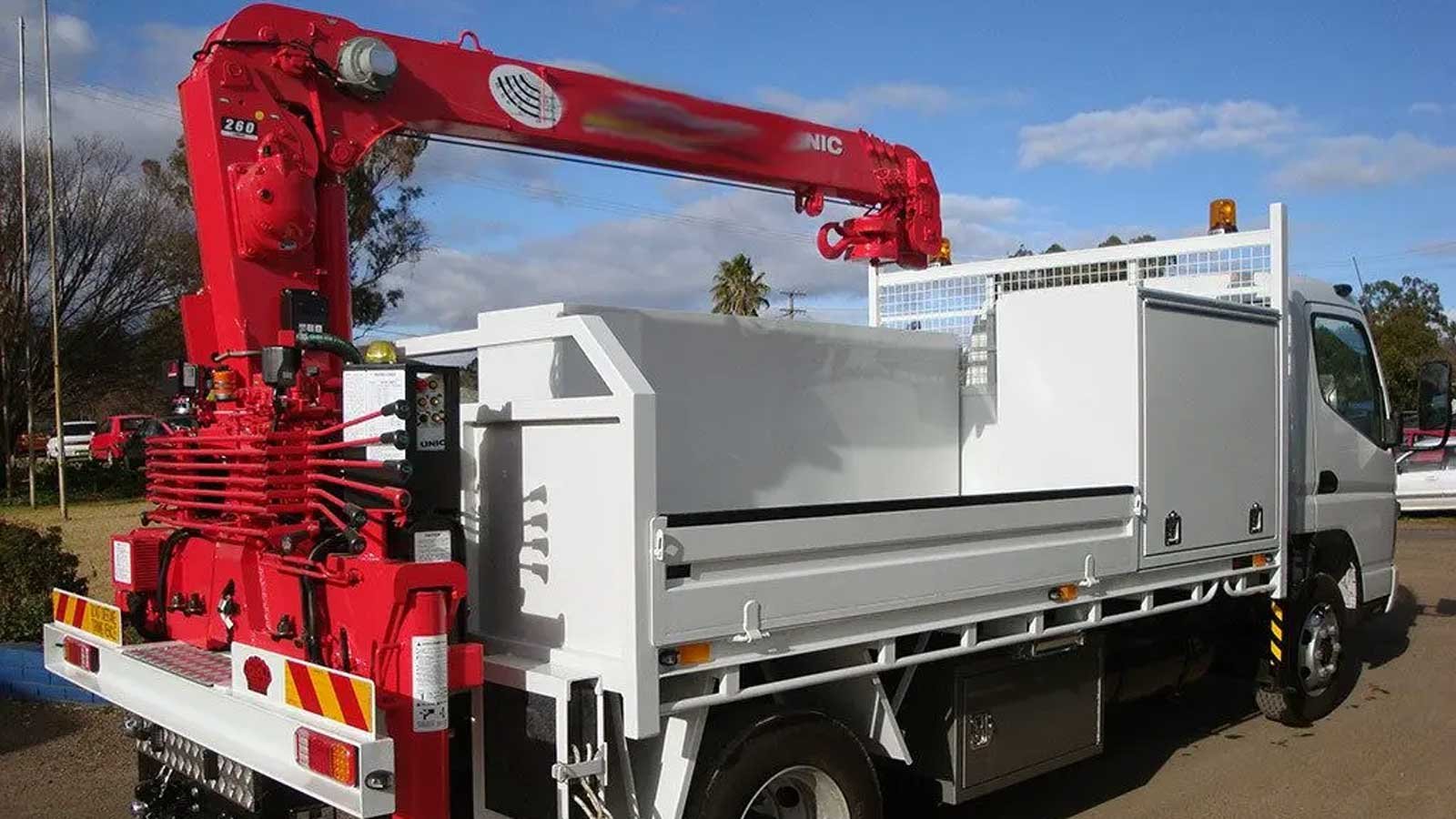 White truck with red crane attachment arm on the back