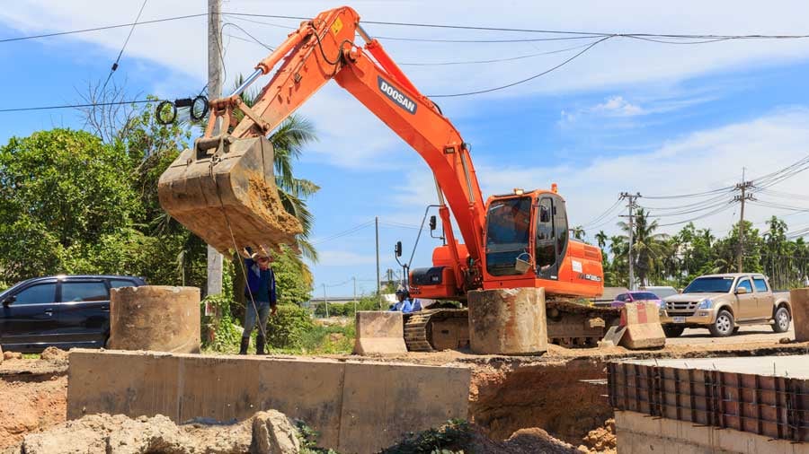 Heavy machinery lifting dirt near powerlines