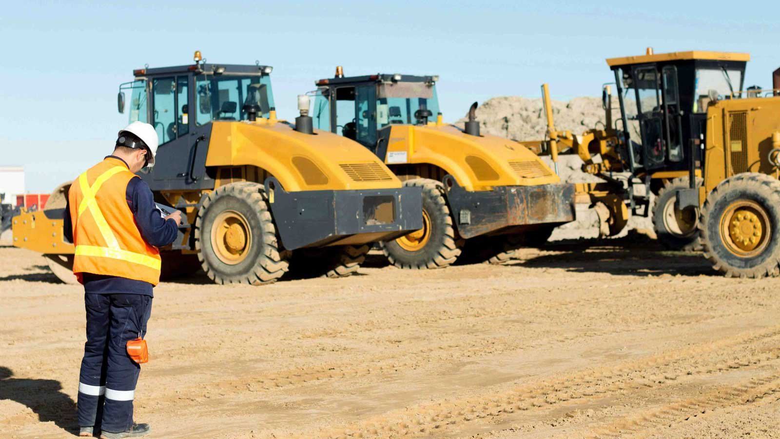 Man in high vis assessing heavy machinery in the background