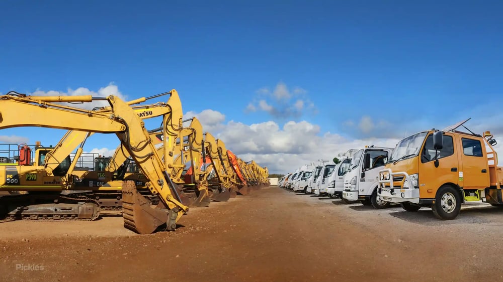 Row of heavy machinery equipment and a row of trucks lined up ready for auction
