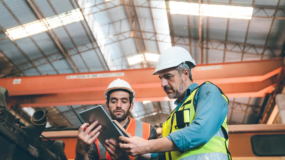 Two men looking at an ipad in a manufacturing warehouse