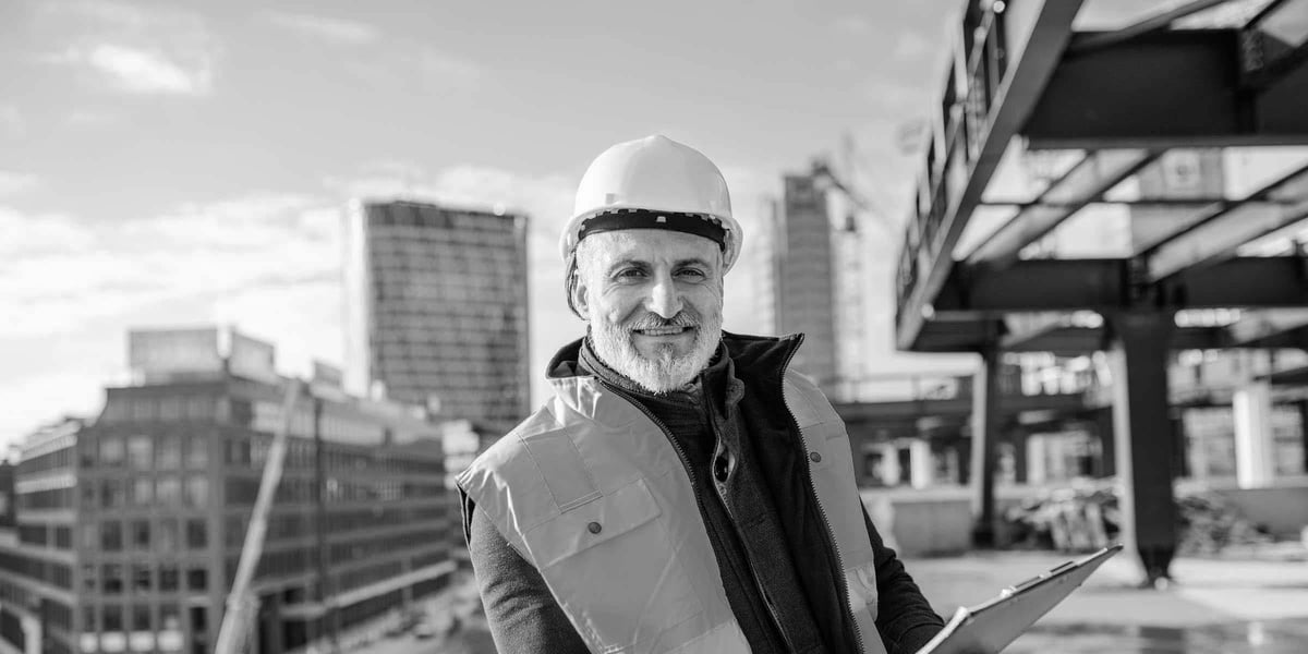 Construction engineer standing with clipboard with building site in background