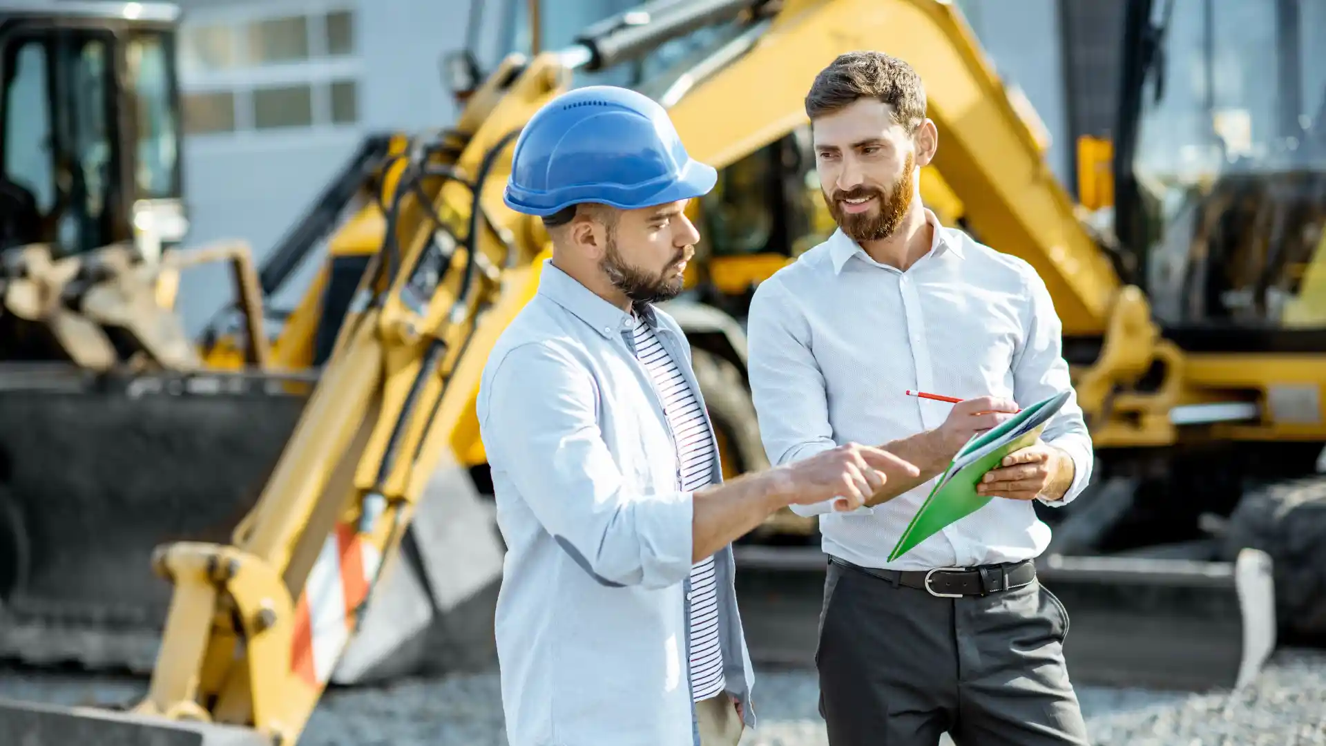 Man wearing helmet talking to other man about machinery details