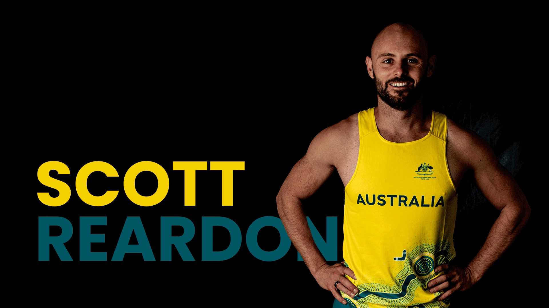 Scott Reardon wearing green and gold athletics gear standing in front of a black background with his name written in green and gold on his left