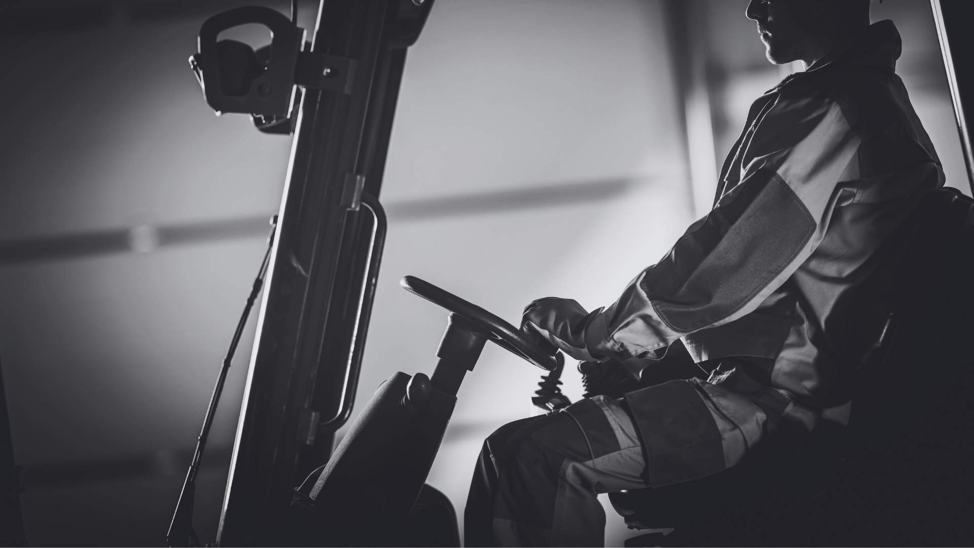 Close up black and white image of a man operating a forklift