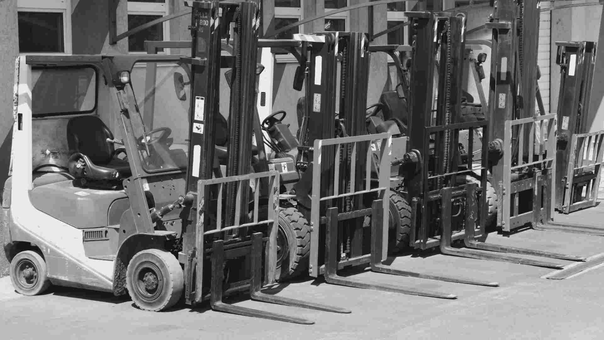 A series of forklifts lined up in a work yard