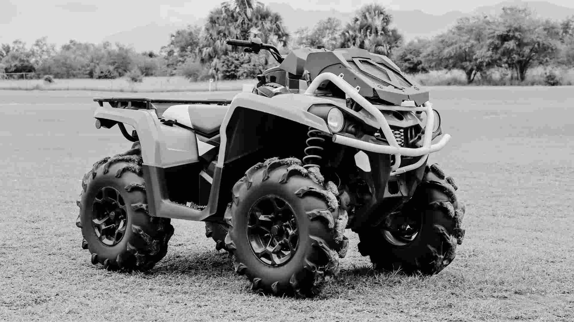 Close up of a quad bike in a grass paddock surrounded by trees