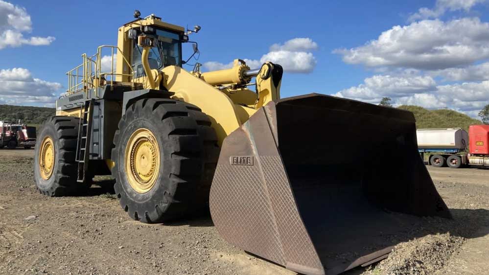 Yellow used front end loader in a dirt yard