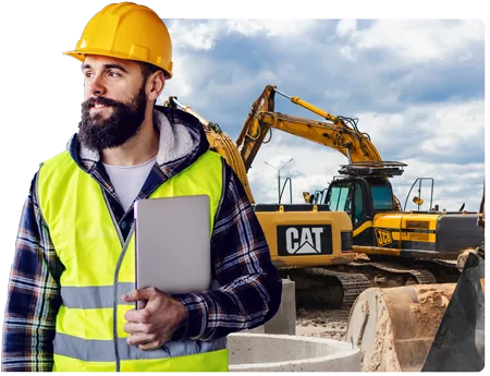 Man holding ipad in PPE overseeing a work site with heavy machinery