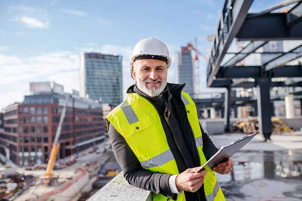 Project engineer with a clipboard overseeing a construction site