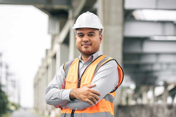 Project manager with crossed arms wearing hard hat and hi-vis