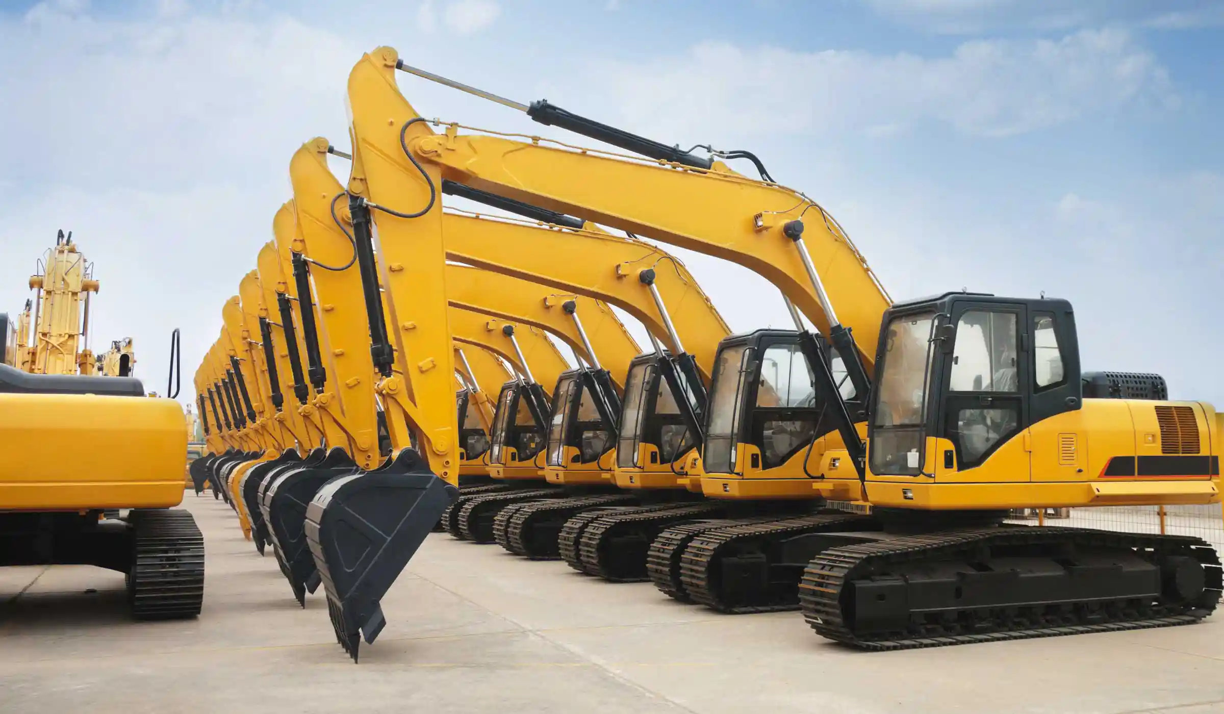 A lineup of yellow and black excavators at a machinery dealer