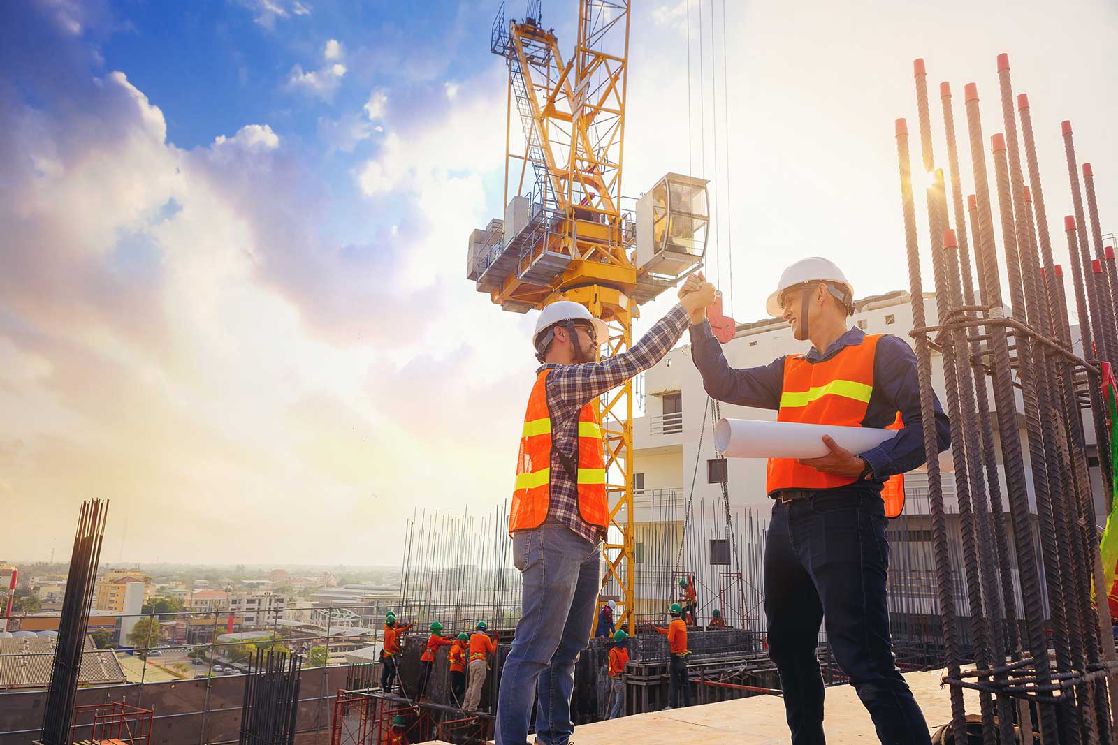 Two men in high vis high-fiving on a construction site