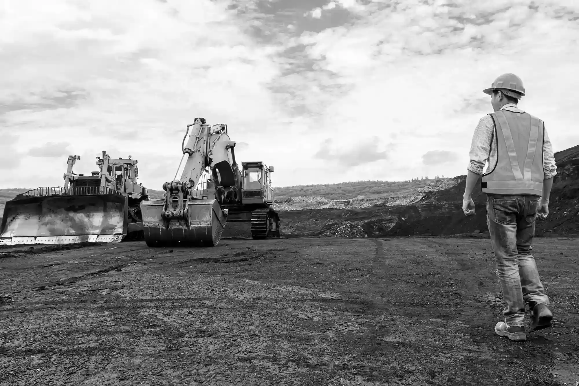 Man overlooking two heavy machines on a work site