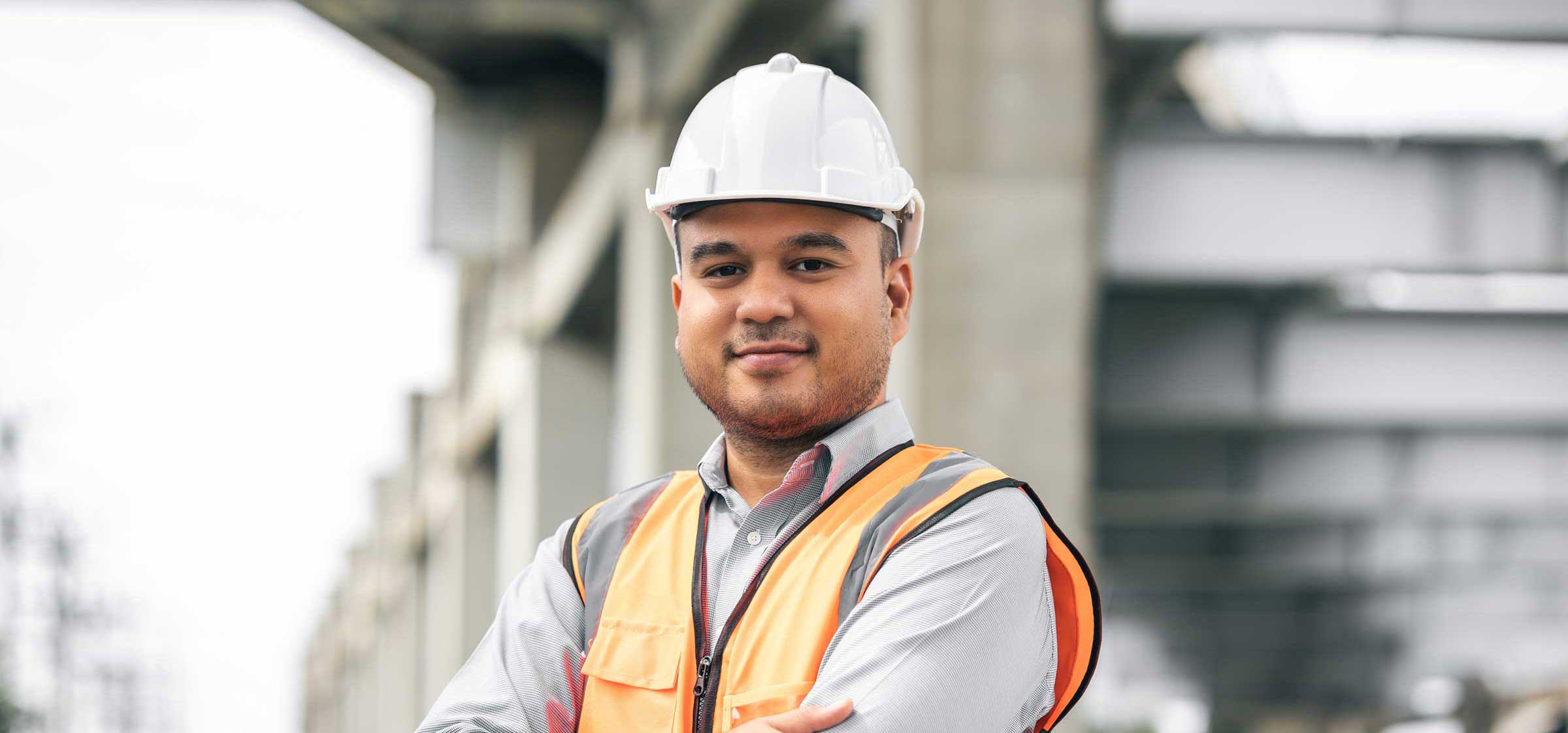 Project Manager in hi vis and safety helmet with buildings in background